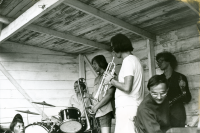 Festligheter vid Frösunda festplats i juli 1973. Bandet spelar New Orleans-musik att dansa till. Konstnären Ulf Gripenholm på trummor, namn på övriga musikanter är okänt men ska enligt uppgift var hans "kollegor".
•Fotografiet ingår i bildserien ”Vardagsliv i Vallentuna kommun” av Rachael Gough-Azmier & Gunilla Blomé, Haga Studios HB.