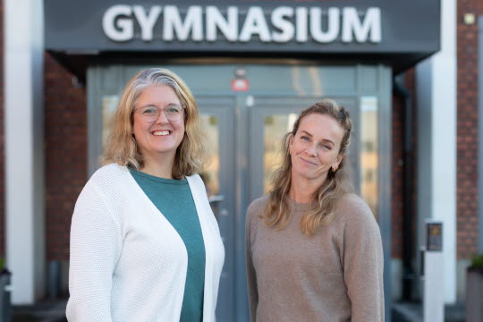 Porträtt av Linda och Julia framför ingången till Vallentuna gymnasium