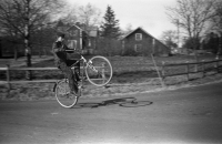 Per-Erik Asplund stegrar sin cykel vid vägskälet utanför Lillgården, Bönhuset skymtar i bakgrunden vid vägen ner mot Ekskogens station. Uppgift om fotoår saknas men troligen mitten av 1950-talet.