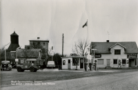 Begsättra i Angarn med café och Shell bensinstation. När bilden togs var Erik Nilsson innehavare (text på fotot). Här har också Seth Abel Axén (1899-1986) drivit café och bensinstation tillsammans med hustrun Ruth (1904-2003) samt systern Olga Axén (död 1951). Seth började med en kiosk på 1930-talet. 1947 byggdes fastigheten om. Kopia av ett vykort.