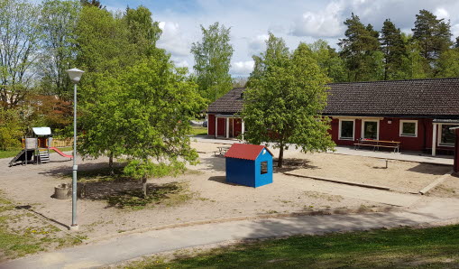 Utemiljö för Smultronet förskola med ett litet blått hus i mitten.