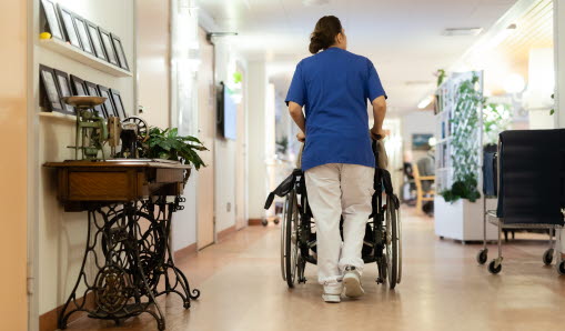 Medarbetare på äldreboende drar kund i rullstol