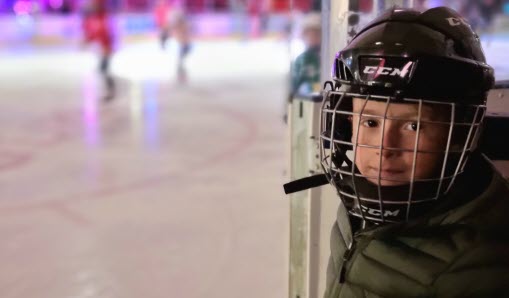 En pojke i hockeyhjälm är på väg att gå ut på isen i Vallentuna ishall.