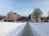 Vy mot Centralvägen sett från Prästgårdsparken som är täckt av snö. Flerfamiljshusen byggdes här i början av 1950-talet. Centralvägen med bostäder och affärslokaler brukar kallas Vallentunas första affärsgata.