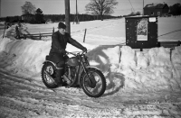 "Prelle" kom från Lindholmen till Kårsta på sin  motorcykel, en BSA 500. I bakgrunden syns bönehuset vid Ekskogen, gården bakom är Mälsta gård på kullen i vägskälet vid Lillgården. Uppgift om fotoår saknas, troligen mitten av 1950-talet.