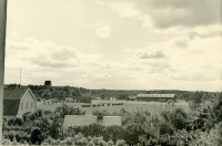 Vy från Vänbo på Tvärvägen 83, fotat från balkongen, kallat "Kokmors hus". Till vänster skymtar taket på Vallentuna kyrka. I bakgrunden syns prästgårdens ladugård.