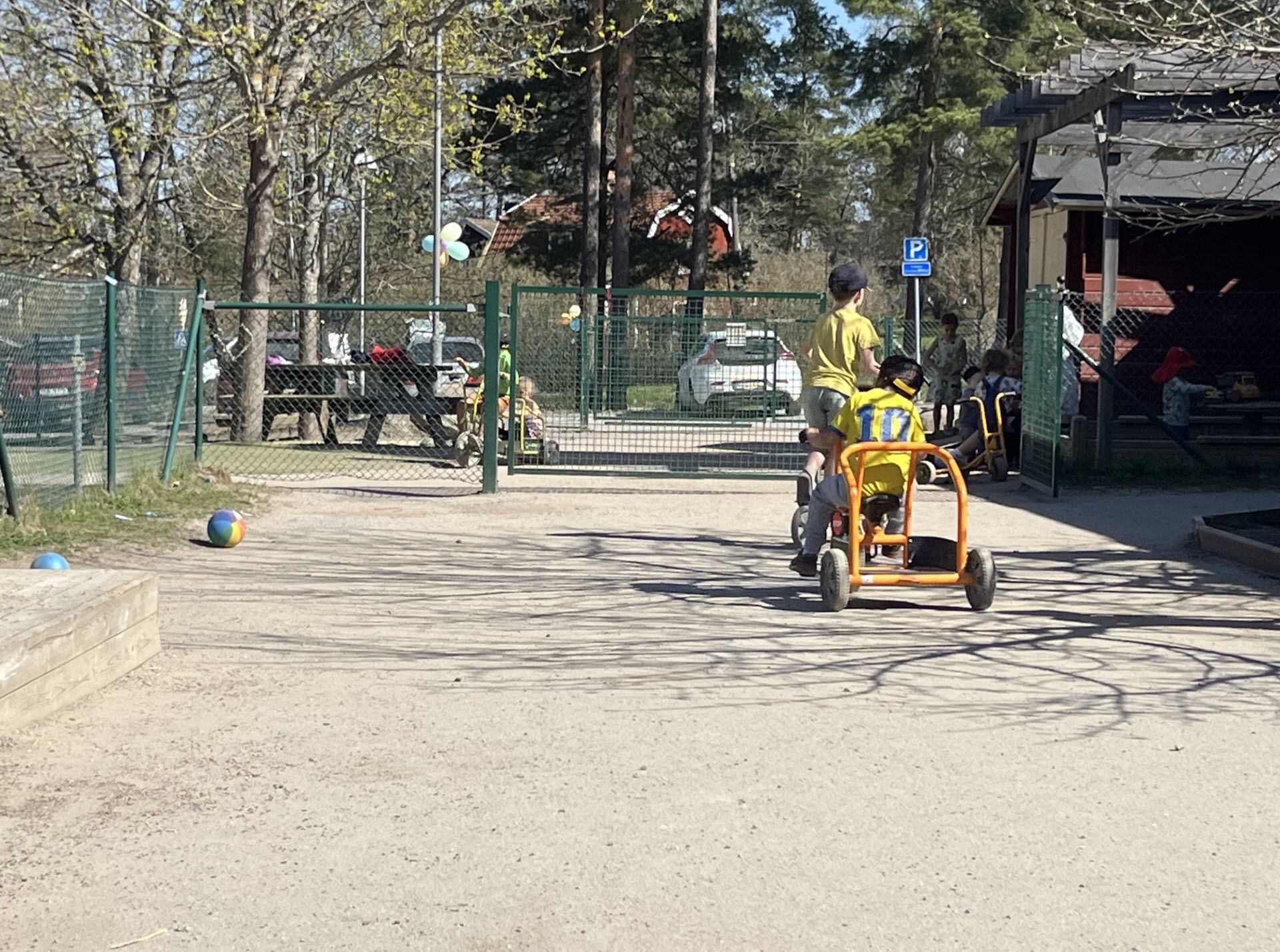 Öppen bild på Kårsta förskolas utemiljö med en barn som cyklar.