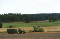 Traktor med släp och en skördetröska i arbetet med skörden på en åker i Markim i augusti 1997.