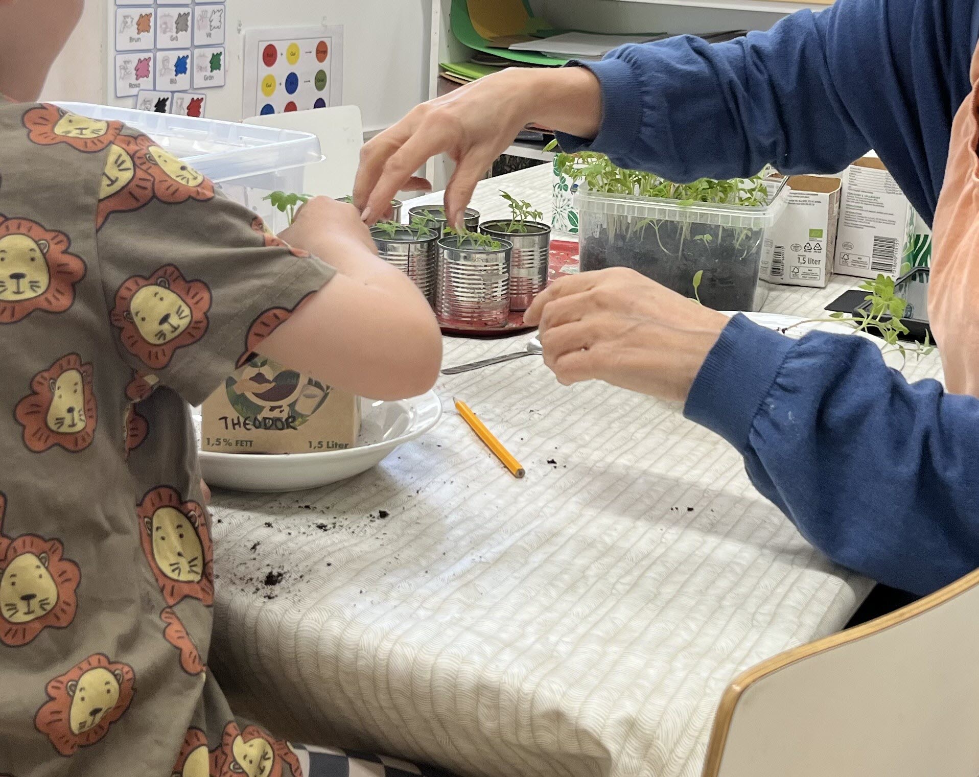 Barn och pedagog planterar växt i pappkruka.