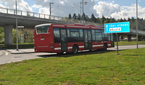 Röd buss som körs längs med vägen.