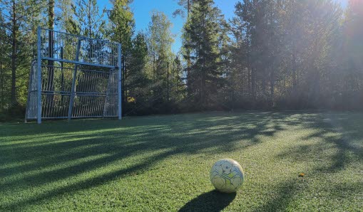 En vit fotboll på en fotbollsplan utomhus.