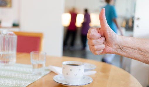 Tumme upp ovanför en kaffekopp