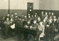 Skolfotografi Hjälmsta skola, interiör från Vita skolan. Lärarinnan Edit Lindström fotograferas med klass 3 1930. Lärarinnan sitter lite dold längst bak.