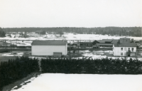 Utsikt från villa Marieborg i centrala Vallentuna på vintern med snötäcke. Husfasaden till vänster, som saknar fönster, tillhör biografen "Centrumbio". Det vita huset till höger var "Wivangers hus" med frisersalong.