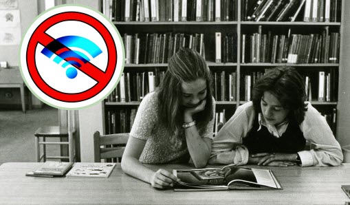 Två personer sitter i bibliotek och läser tidning, 1971, plus en inmonterad symbol för wifi som är inringad och överstruken med rött.