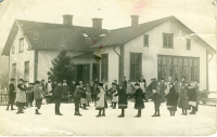 Stångberga skola vintern 1917. Skolfotografi på skolgården. Bakom barnen syns tre kvinnor stå framför husväggen. Den högra är lärarinnan från bild 8450.