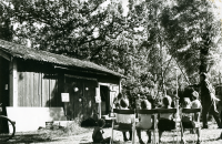 En gårdsfest anordnas för Svenska Missionsförbundets Ungdom, SMU, vid missionskyrkans hus på Olsborgsvägen. Pastor Folke Palmqvist, som syns till höger i bild, är med vid lekarna som anordnas. Här gäller det att pricka porslinet som hänger på väggen. Några barn sitter på stolar och tittar på.
•Fotografiet ingår i bildserien ”Vardagsliv i Vallentuna kommun” av Rachael Gough-Azmier & Gunilla Blomé, Haga Studios HB.